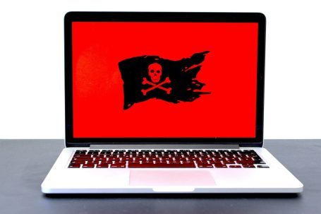 Virenentfernung und IT-Sicherheit für PC & Laptop Laptop mit rotem Bildschirm, darauf eine schwarze Piratenflagge mit Totenkopf.