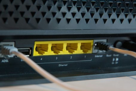 WLAN Optimierung und Internet Einrichtung Oberursel & Köln Detailansicht eines Routers mit fünf Ethernet-Anschlüssen und zwei Kabeln.